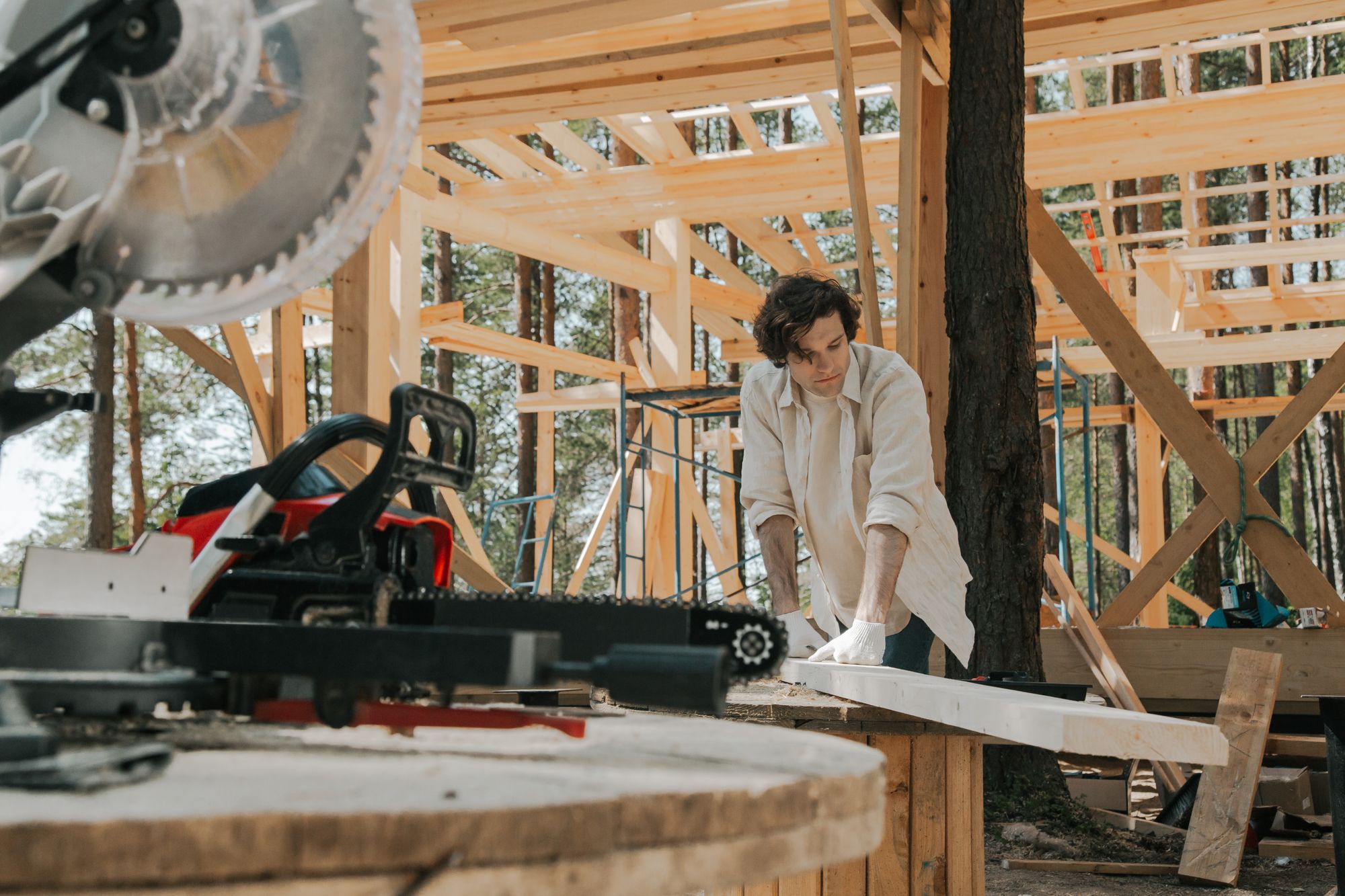 Carpenter working with timber inside a wooden frame under construction