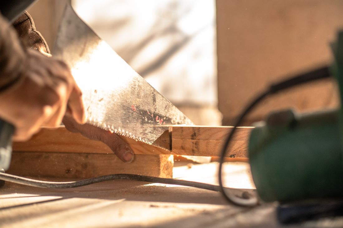 Close-up of a hand saw cutting a marked piece of timber